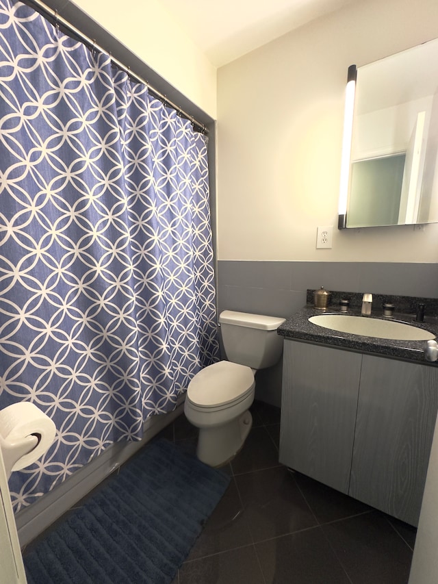 bathroom with wainscoting, tile patterned flooring, vanity, toilet, and tile walls