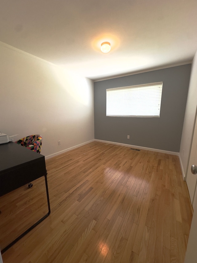 unfurnished bedroom with baseboards, light wood finished floors, and visible vents