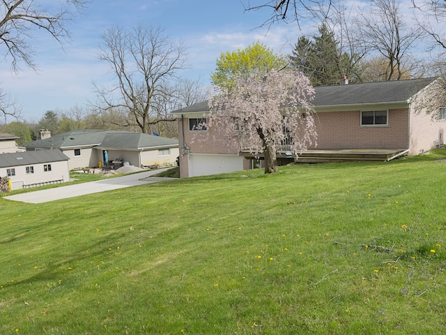 view of yard featuring a wooden deck, an attached garage, and driveway