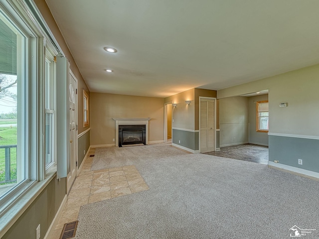 unfurnished living room featuring light carpet, a glass covered fireplace, recessed lighting, baseboards, and visible vents