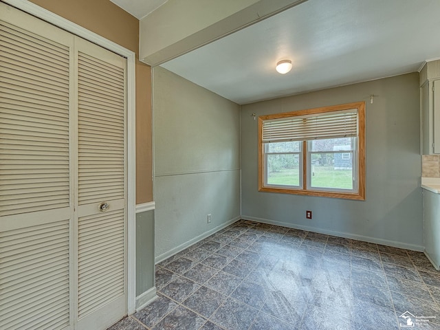 unfurnished bedroom featuring a closet, stone finish flooring, and baseboards