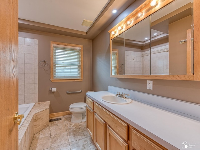 bathroom with visible vents, vanity, toilet, baseboards, and tiled bath