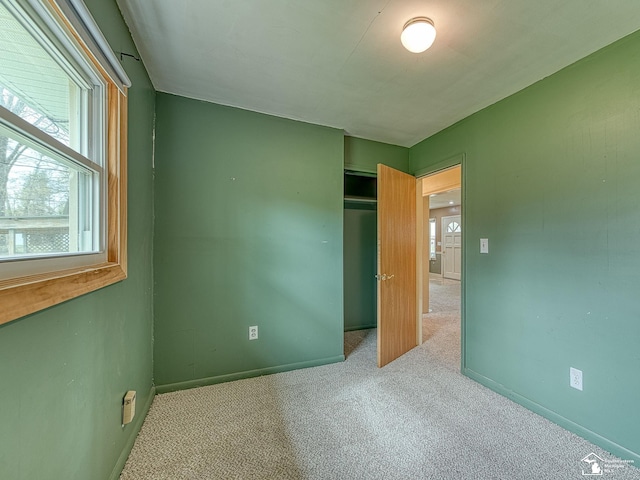 unfurnished bedroom featuring carpet floors, baseboards, and a closet