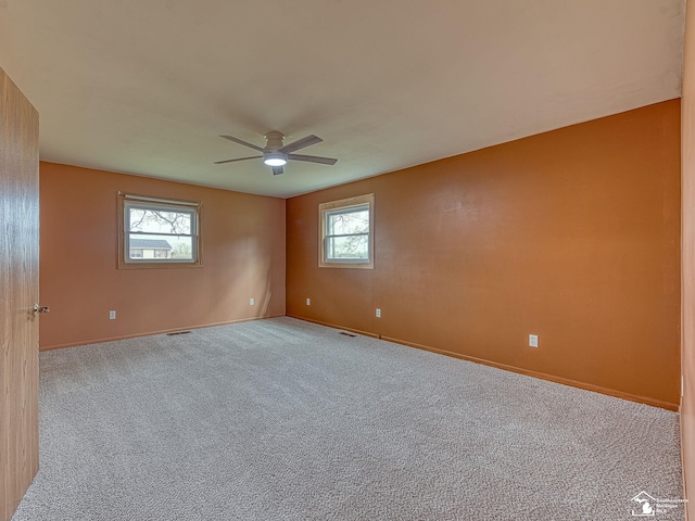carpeted empty room featuring baseboards, ceiling fan, and visible vents