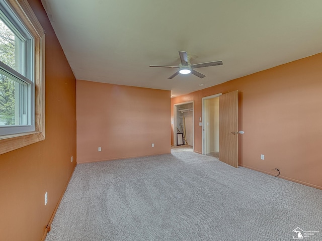 interior space featuring baseboards, multiple windows, carpet, and ceiling fan