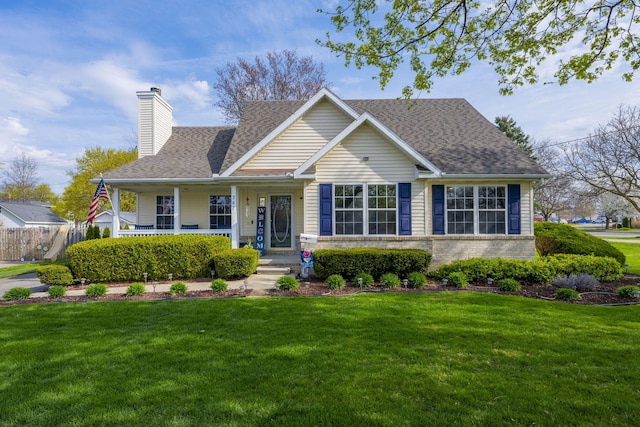 view of front of house with a front lawn, covered porch, roof with shingles, a chimney, and brick siding