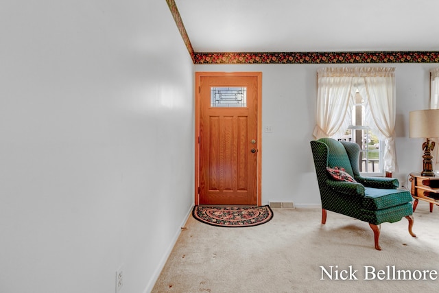 carpeted entryway with baseboards, visible vents, and a healthy amount of sunlight