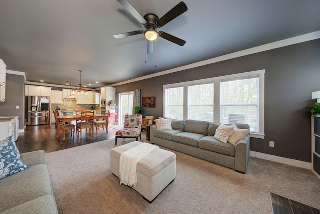 living area with crown molding, dark wood finished floors, ceiling fan with notable chandelier, recessed lighting, and baseboards