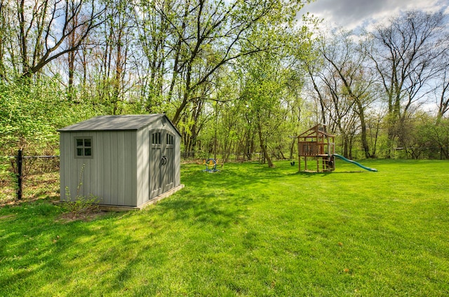 view of yard with a storage unit, a playground, fence, and an outbuilding