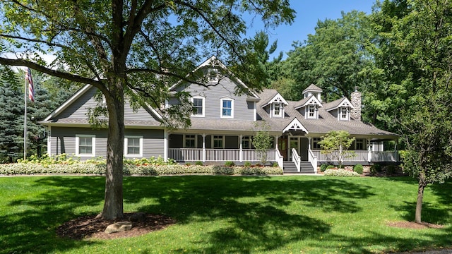 view of front of house with covered porch, a front lawn, and a chimney