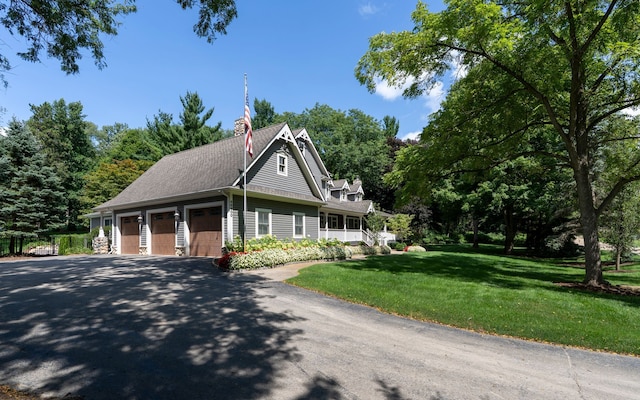 farmhouse-style home with a shingled roof, a garage, driveway, and a front yard