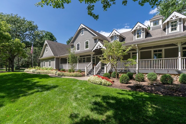 view of front of property featuring covered porch, a shingled roof, and a front lawn