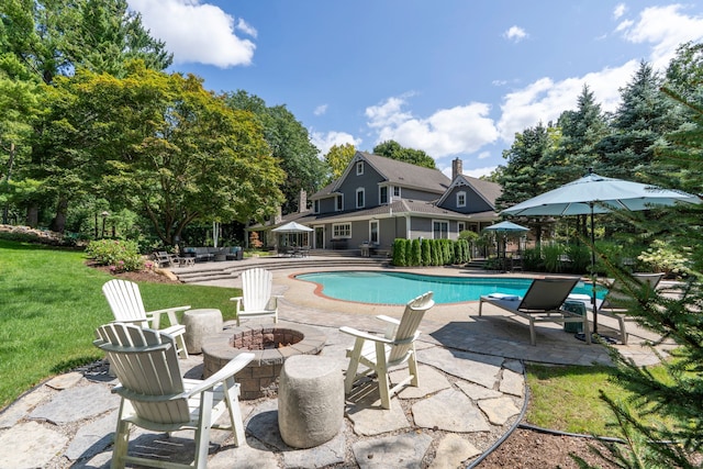 outdoor pool with a yard, a patio, and an outdoor fire pit