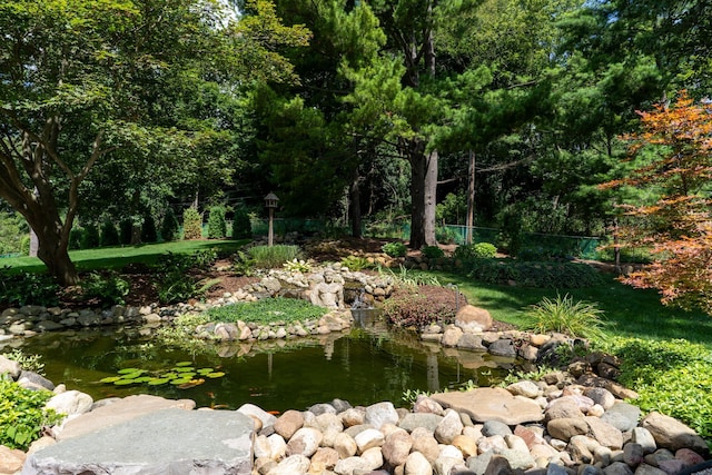 view of yard featuring fence and a garden pond