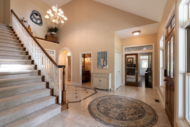 foyer featuring light tile patterned flooring, high vaulted ceiling, stairway, arched walkways, and baseboards
