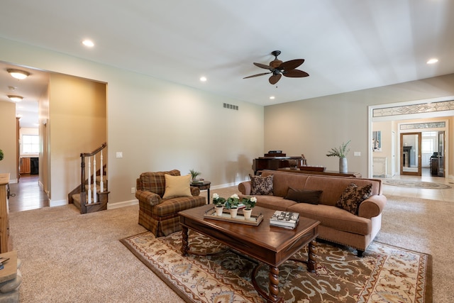 carpeted living room with recessed lighting, visible vents, ceiling fan, and stairway