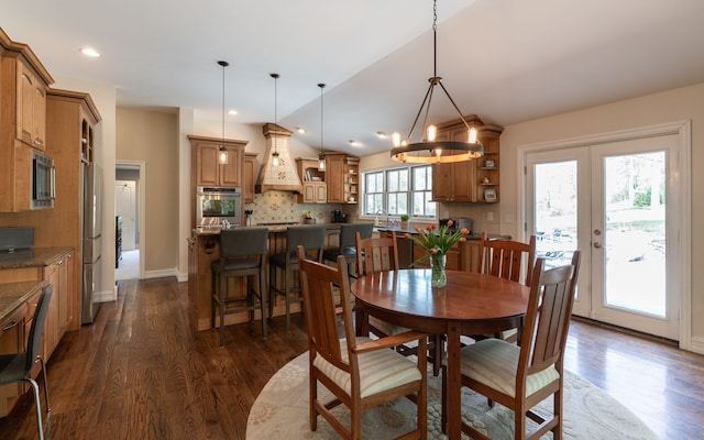 dining area featuring dark wood finished floors, french doors, baseboards, and a notable chandelier