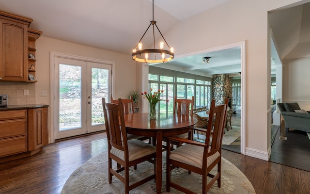 dining space featuring an inviting chandelier, french doors, dark wood finished floors, baseboards, and lofted ceiling