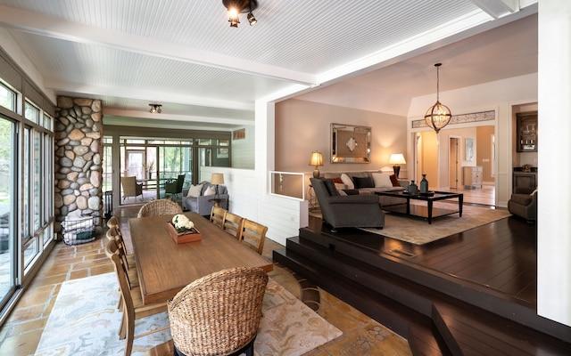 dining area featuring beam ceiling and stone tile flooring