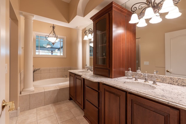 full bathroom with tile patterned floors, a garden tub, decorative columns, and a sink