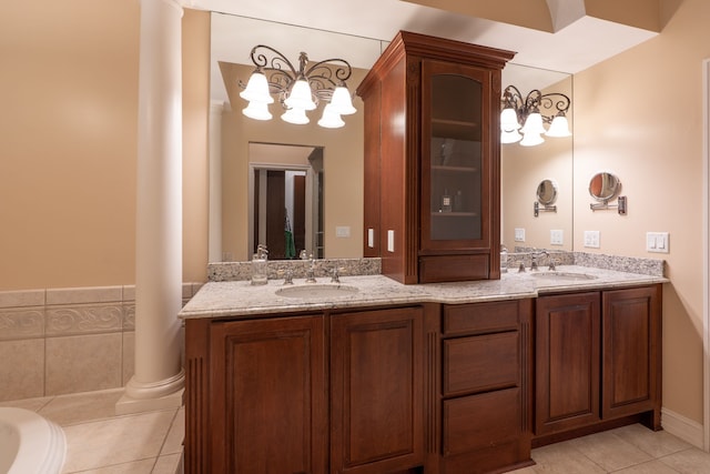 bathroom with tile patterned floors, an inviting chandelier, a sink, and ornate columns