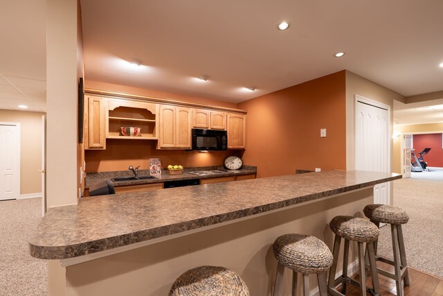 kitchen with a sink, dark countertops, a kitchen breakfast bar, light brown cabinets, and black microwave