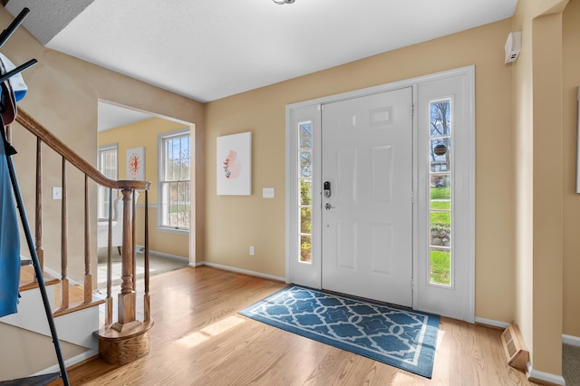 foyer entrance with baseboards, stairs, and wood finished floors