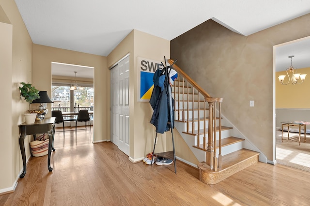 entrance foyer featuring stairs, baseboards, a chandelier, and wood finished floors