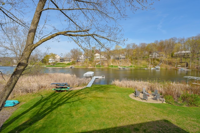 dock area with a yard, a water view, and a fire pit
