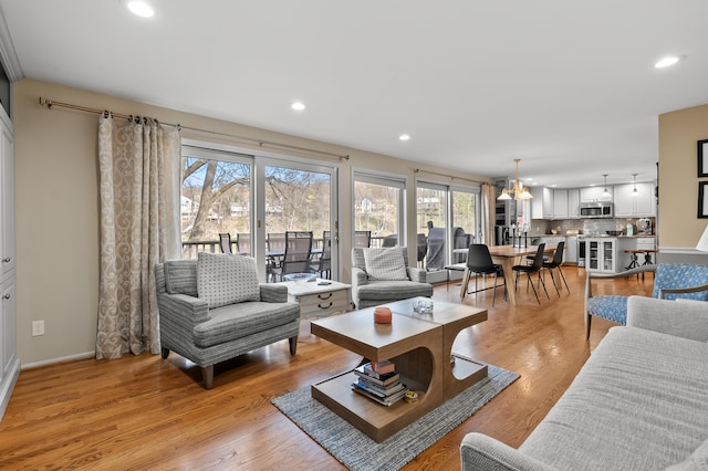 living room with recessed lighting, an inviting chandelier, and light wood-type flooring