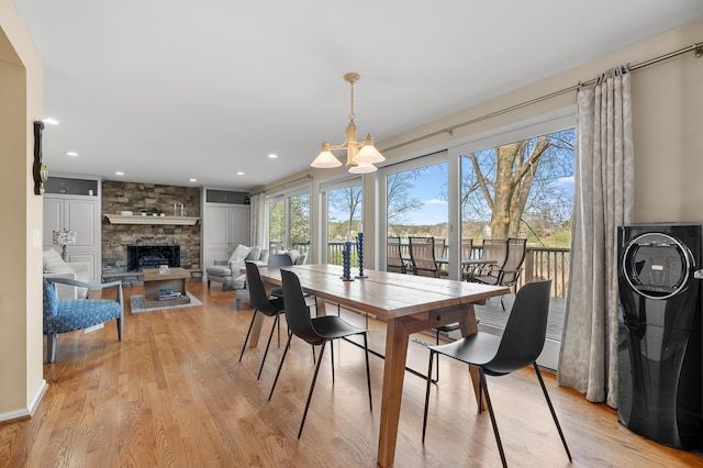 dining room featuring a stone fireplace, recessed lighting, and light wood-style floors