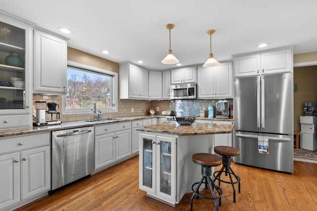 kitchen featuring light wood-style floors, a sink, decorative backsplash, and stainless steel appliances