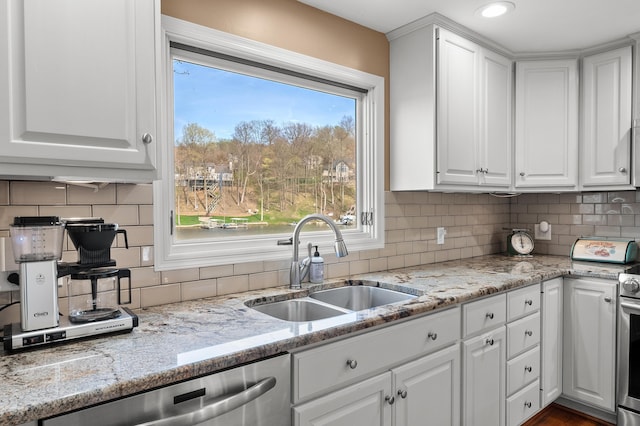kitchen featuring white cabinets, light stone countertops, a sink, dishwasher, and decorative backsplash