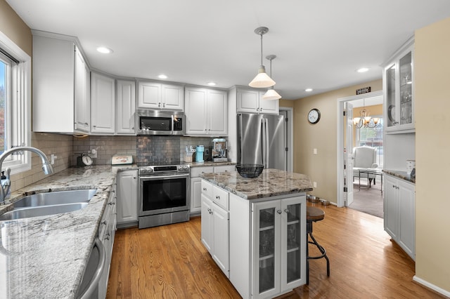 kitchen with a sink, decorative backsplash, appliances with stainless steel finishes, and light wood-style flooring