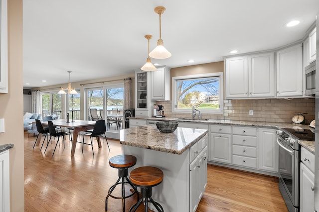 kitchen featuring decorative backsplash, a breakfast bar area, a sink, stainless steel appliances, and white cabinetry