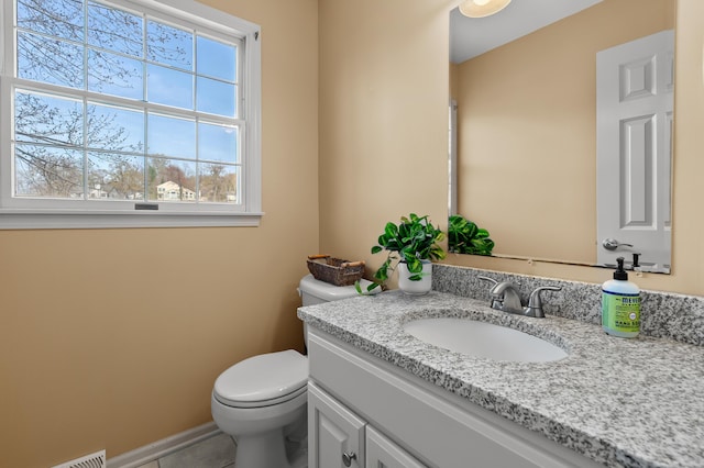 half bath featuring vanity, tile patterned floors, baseboards, and toilet