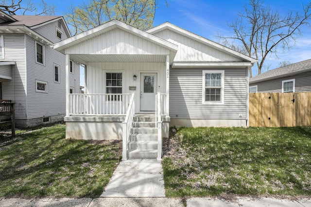 bungalow-style house featuring fence, board and batten siding, a porch, and a front lawn