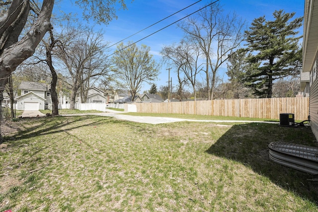 view of yard with central AC, fence, and a residential view