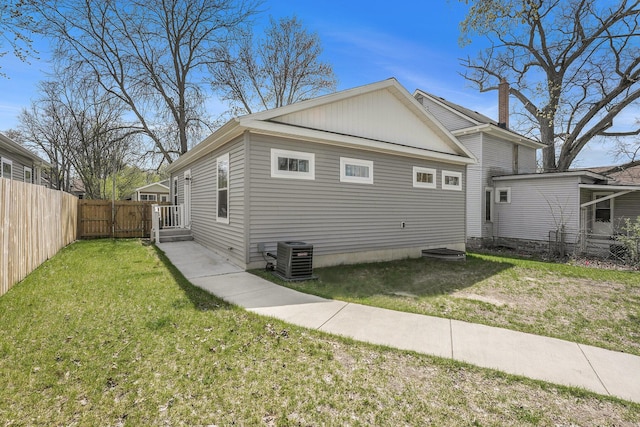 view of side of property featuring fence, a gate, central AC unit, and a yard