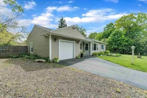single story home featuring an attached garage, fence, a front yard, and aphalt driveway
