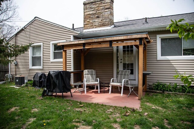 back of house featuring a lawn, a patio, cooling unit, and a chimney