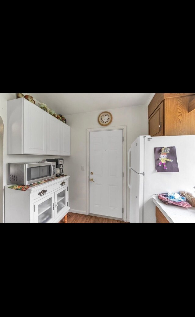 kitchen featuring freestanding refrigerator, light countertops, stainless steel microwave, and light wood-type flooring