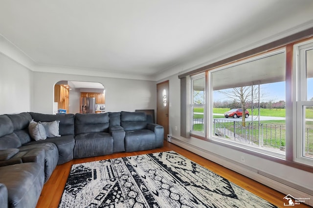 living area with baseboards, arched walkways, light wood finished floors, and baseboard heating