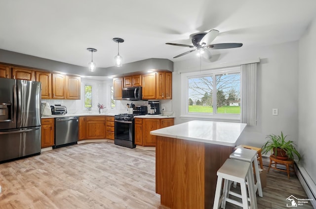 kitchen with light countertops, stainless steel appliances, baseboard heating, and light wood-style flooring