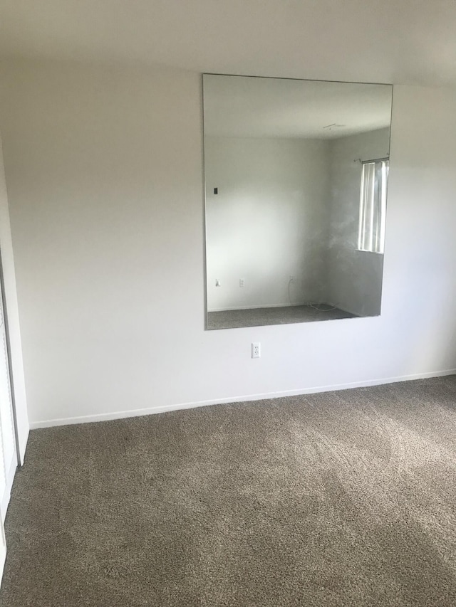 empty room featuring baseboards and carpet