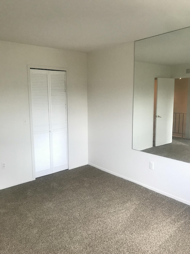 unfurnished bedroom featuring a closet, baseboards, and dark colored carpet