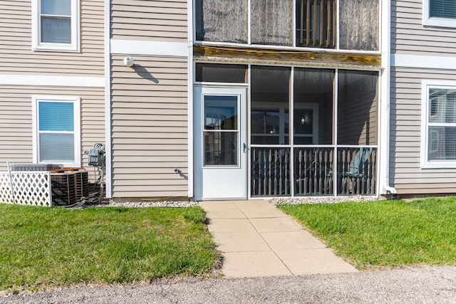 property entrance featuring a lawn and central AC unit