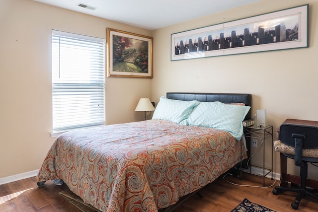 bedroom with visible vents, baseboards, and wood finished floors