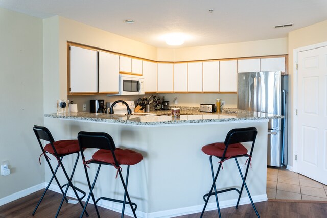 1533 Weatherstone Dr, Ann Arbor, MI 48108 - kitchen featuring white microwave, freestanding refrigerator, a kitchen breakfast bar, range, and light stone countertops