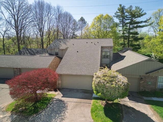 exterior space featuring brick siding, a shingled roof, and concrete driveway
